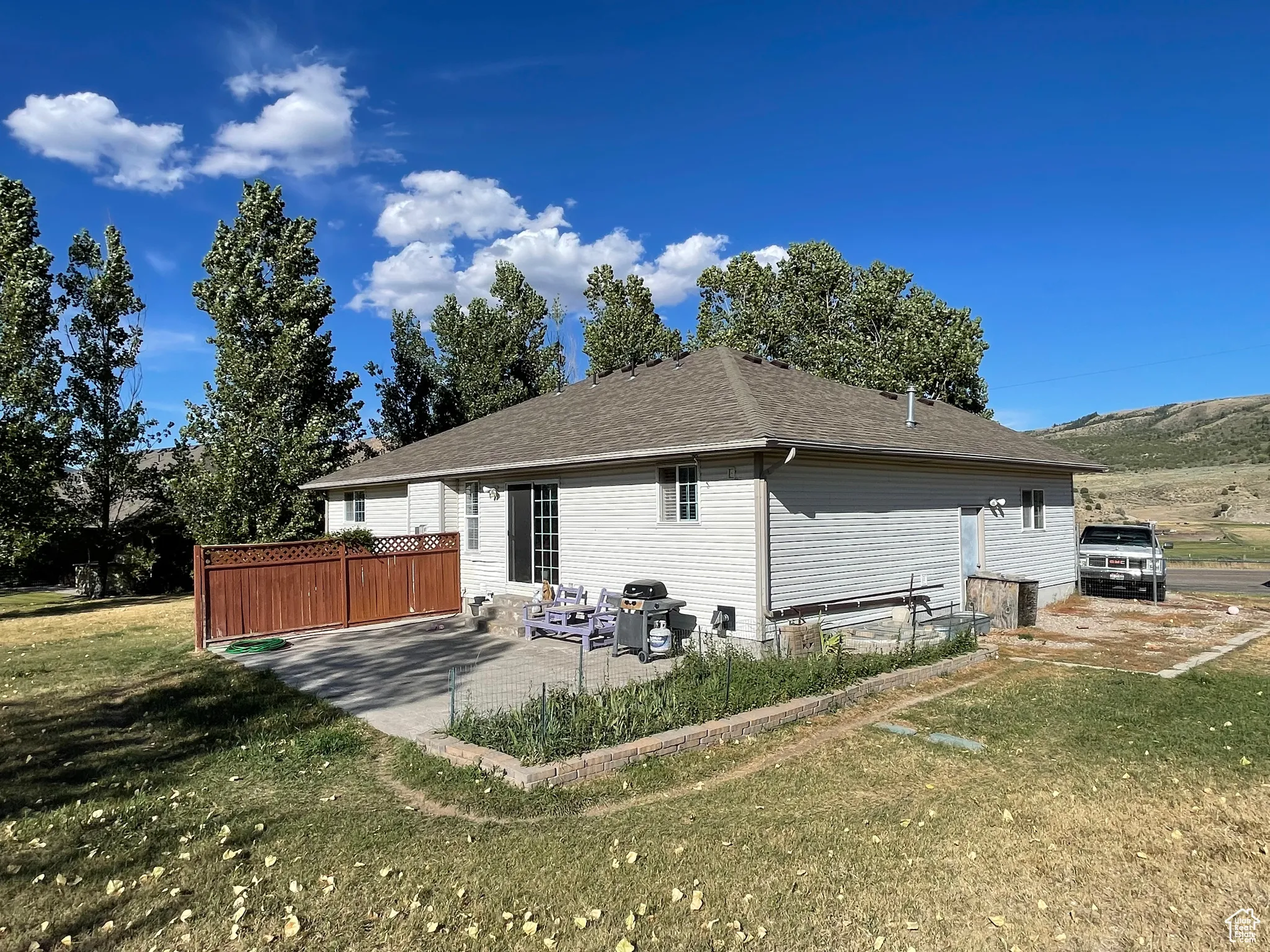 Rear view of property featuring a patio, a shingled roof, and a lawn