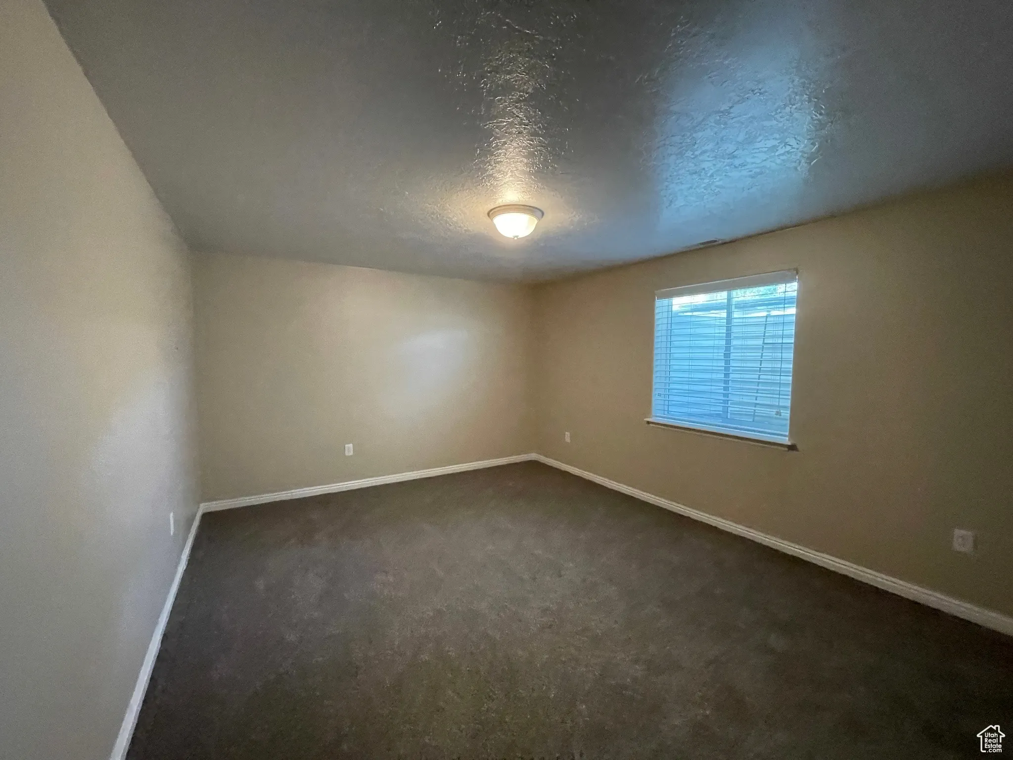 Empty room featuring a textured ceiling and dark carpet