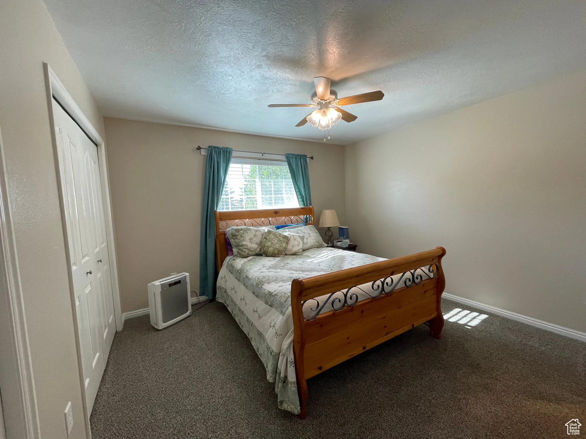 Bedroom featuring carpet floors, a textured ceiling, a closet, and ceiling fan