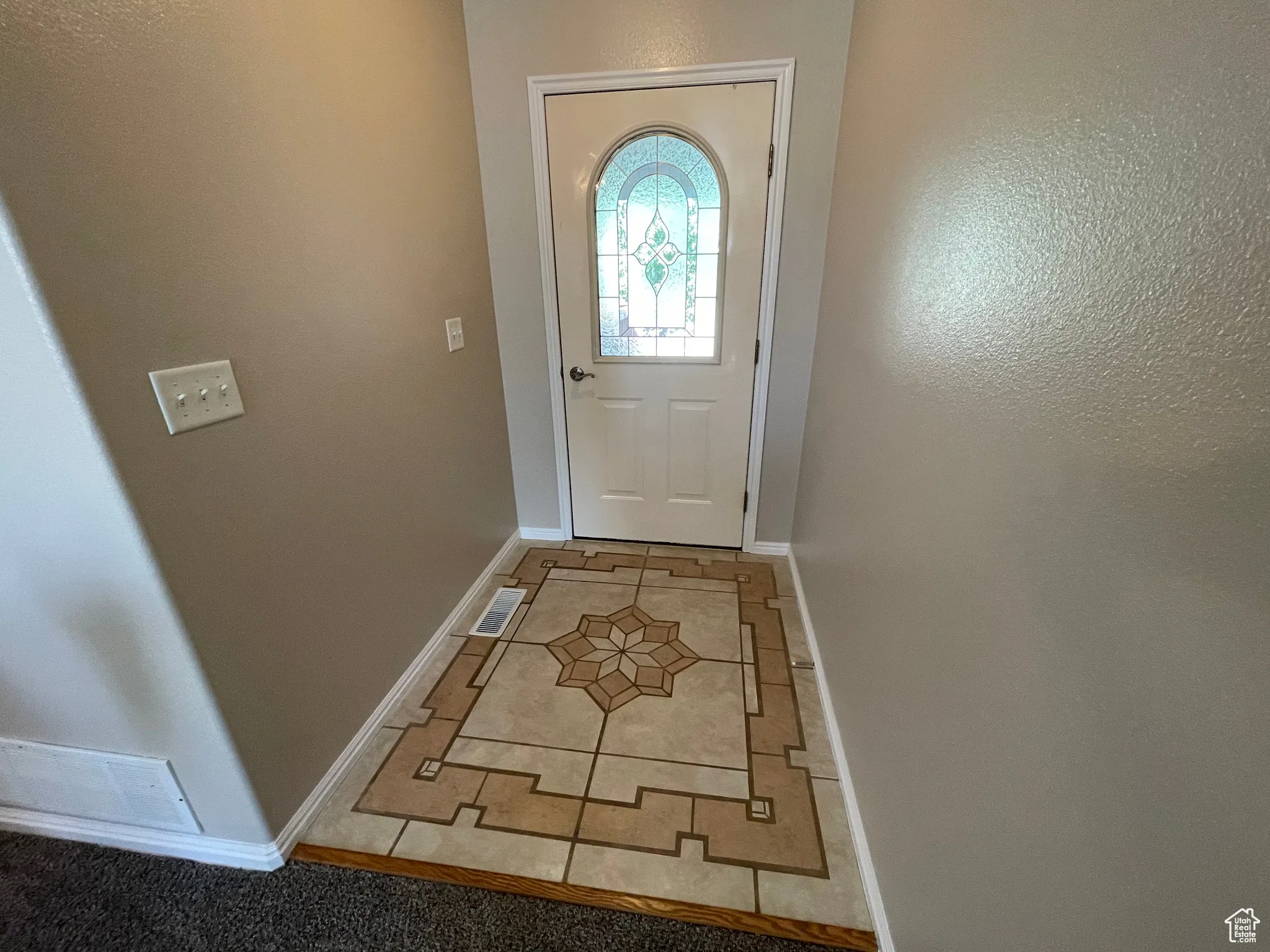 Doorway with light tile patterned floors and a textured wall