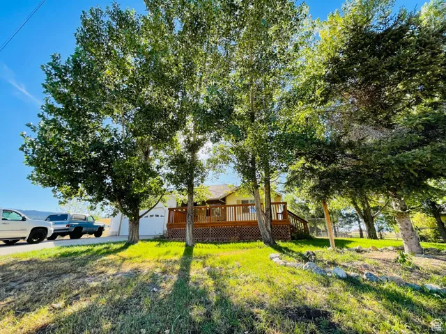 View of front facade featuring a deck, a garage, a front yard, and an outdoor structure