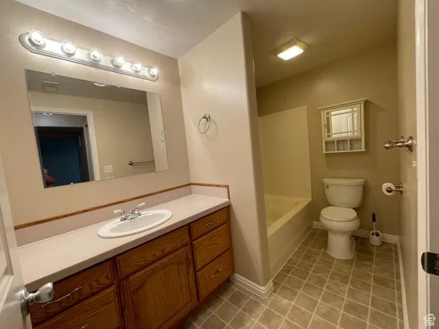 Full bath featuring tile patterned floors, vanity, and a textured ceiling