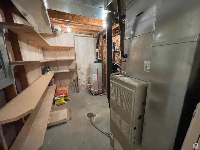Unfinished below grade area featuring heating unit and gas water heater