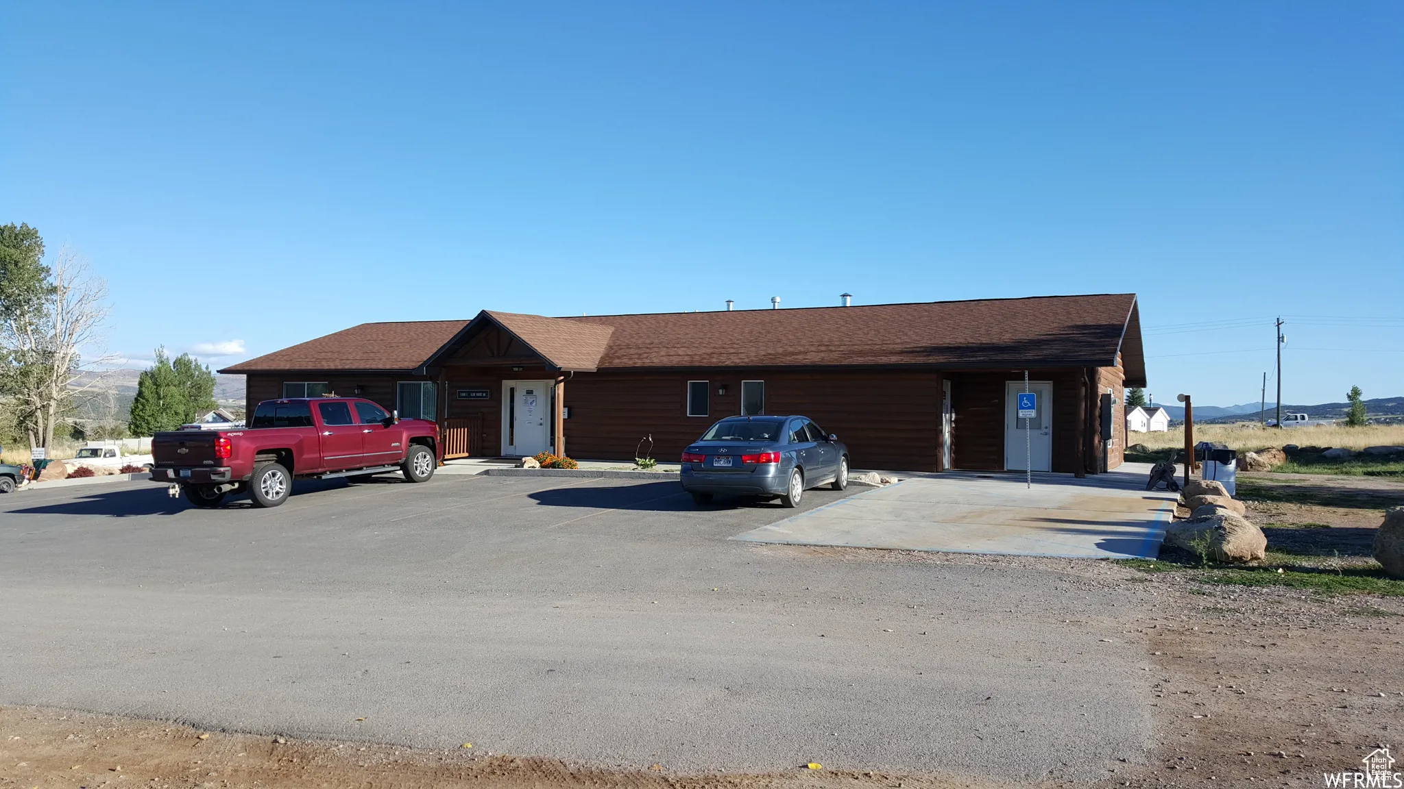 View of front facade with uncovered parking and roof with shingles
