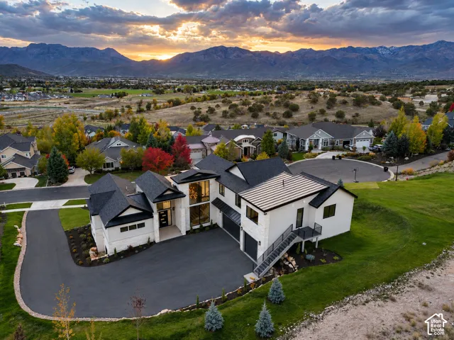 Contemporary residence featuring a black asphalt driveway, a tiered exterior staircase, dark-framed windows, and a multi-level design