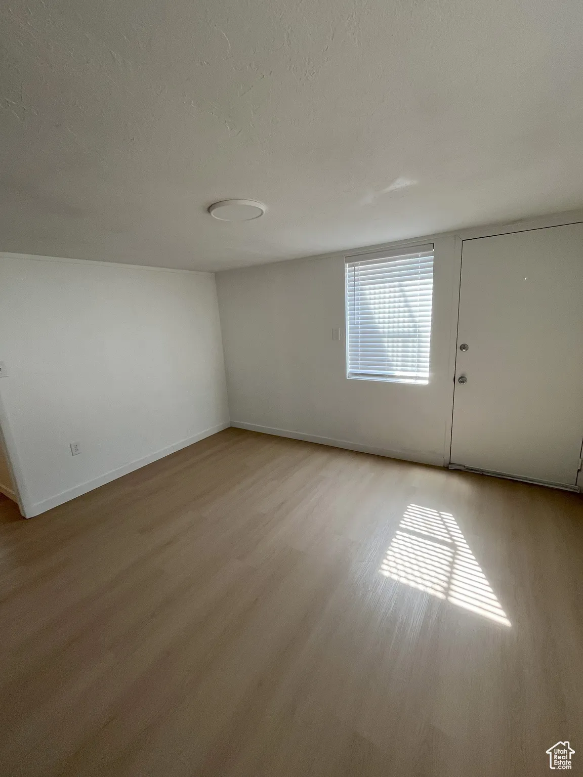 Empty room with light wood finished floors and a textured ceiling