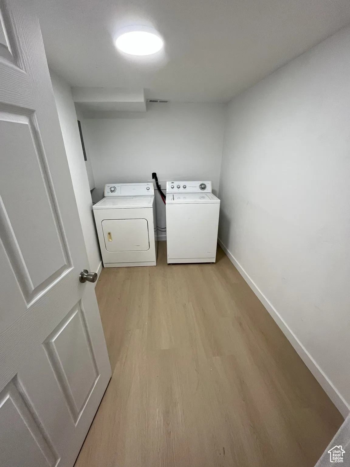 Washroom with light wood-style flooring and separate washer and dryer