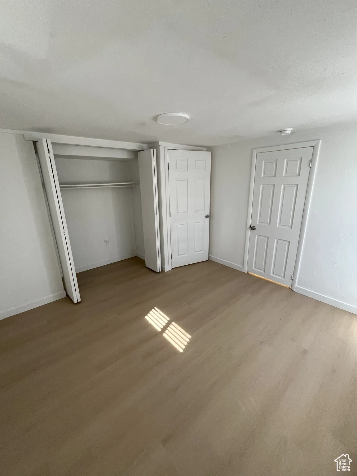 Unfurnished bedroom featuring light wood-type flooring and a textured ceiling