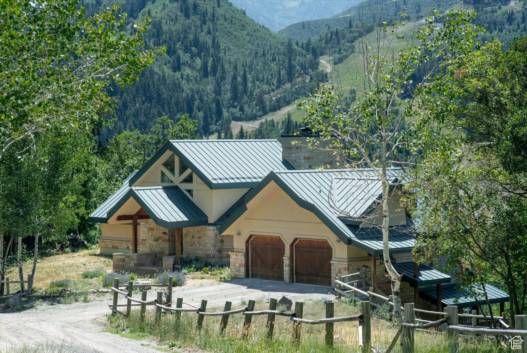 View of front of house with a standing seam roof, dirt driveway, a metal roof, stone siding, and a mountain view