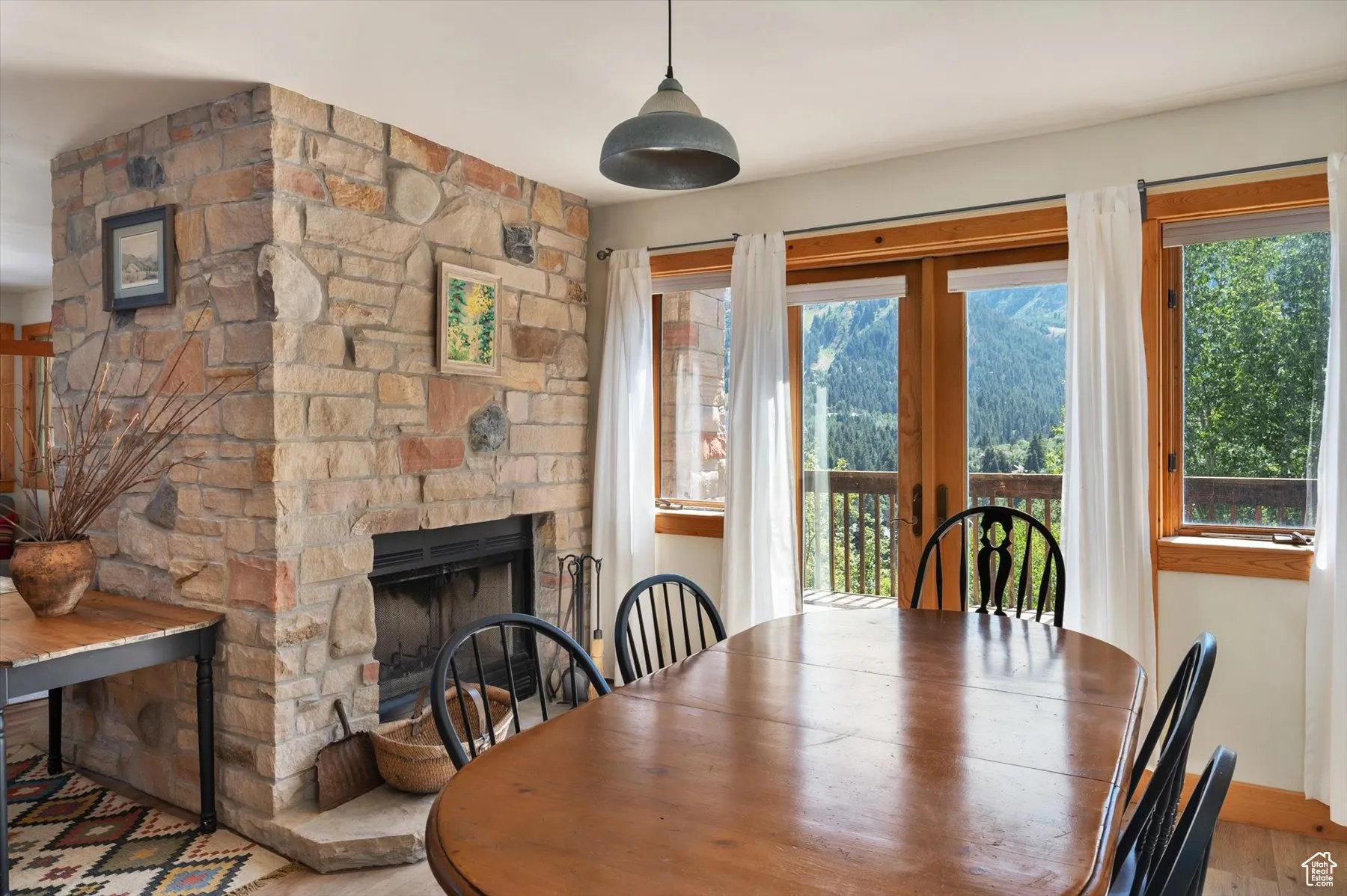 Dining space featuring a stone fireplace and luxury vinyl plank flooring. French doors lead out to a deck with a barbeque