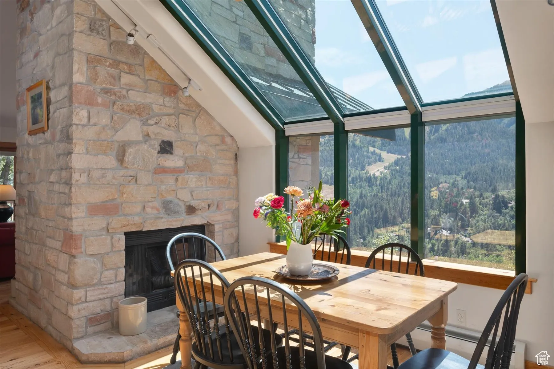 Dining space featuring a fireplace, atrium style windows looking out to jaw dropping views, along with vaulted ceilings