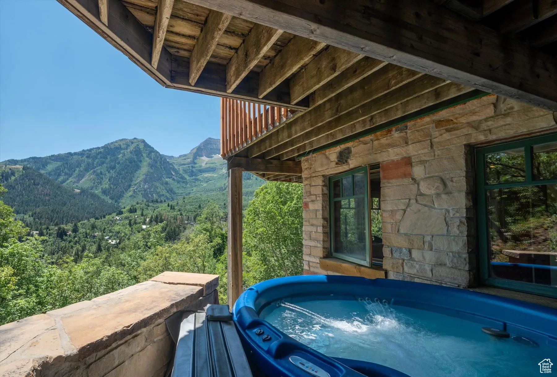 View of patio featuring a mountain view, a hot tub, a view of trees and accessed from the lower level