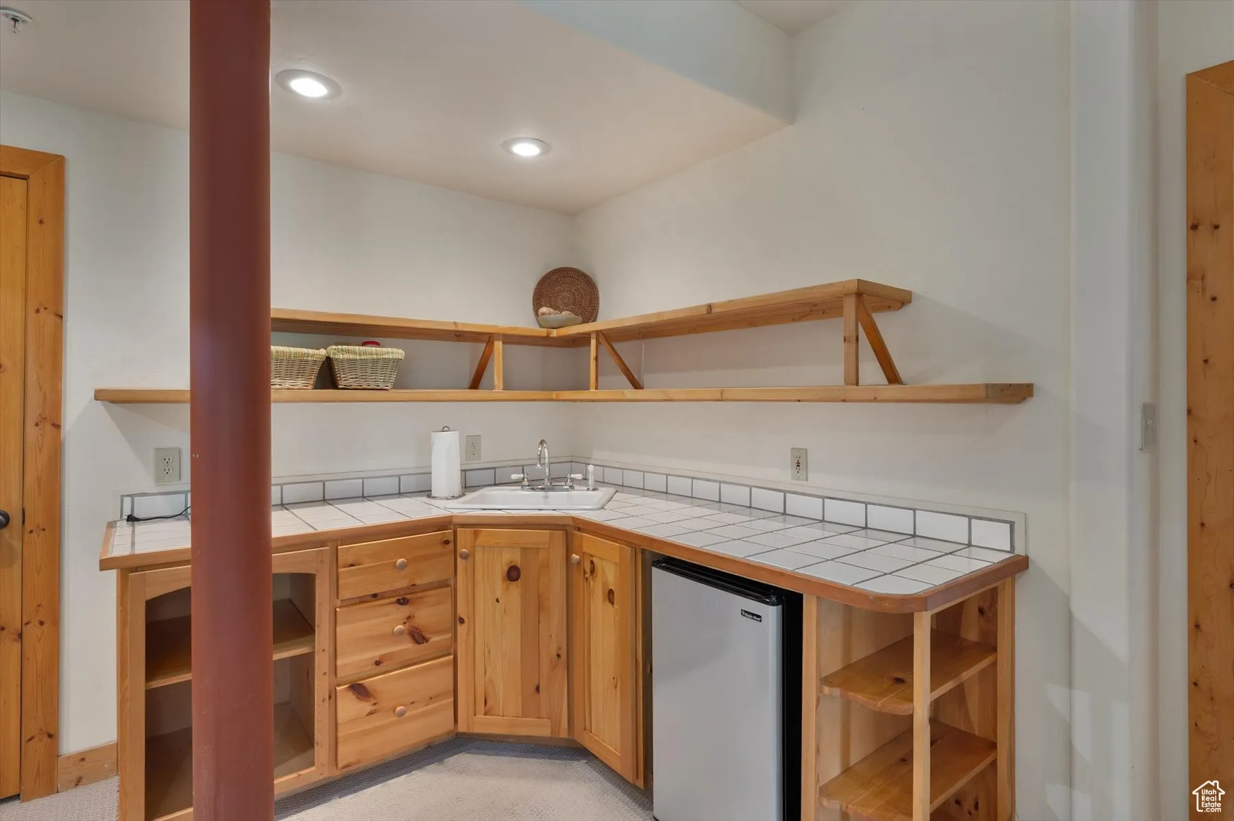 Kitchen featuring open shelves, tile countertops, stainless steel fridge, and recessed lighting