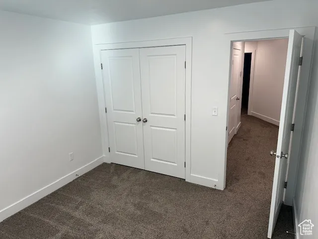 Unfurnished bedroom with dark carpet and a closet