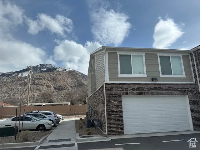 View of side of home with brick siding, a mountain view, and an attached garage