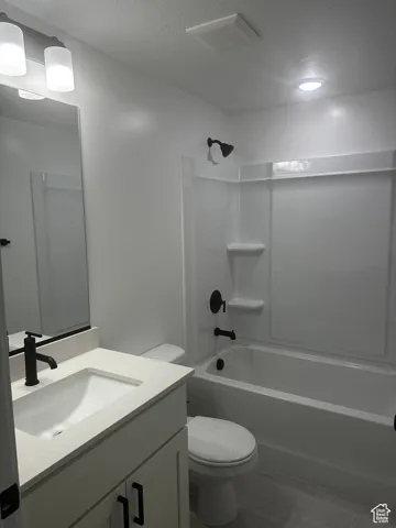 Full bath with a textured ceiling, shower / bathtub combination, and vanity