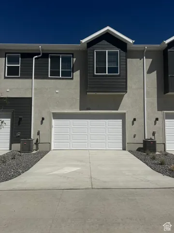 Traditional home with stucco siding, an attached garage, and driveway