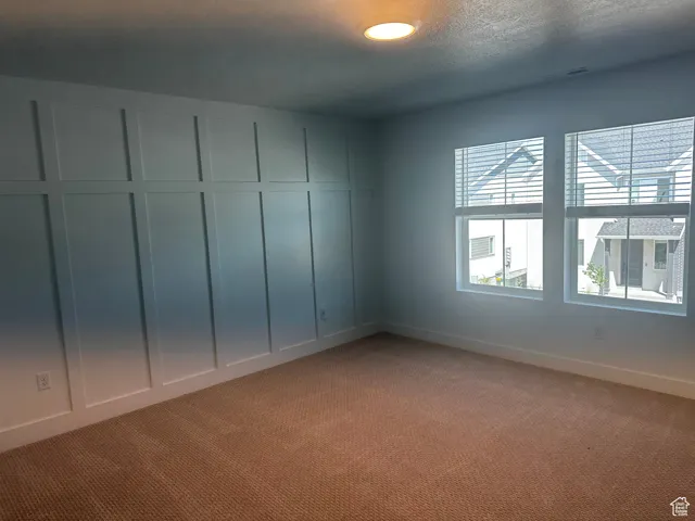 Carpeted empty room with a decorative wall and a textured ceiling