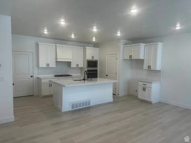 Kitchen featuring backsplash, white cabinetry, custom range hood, a textured ceiling, and recessed lighting