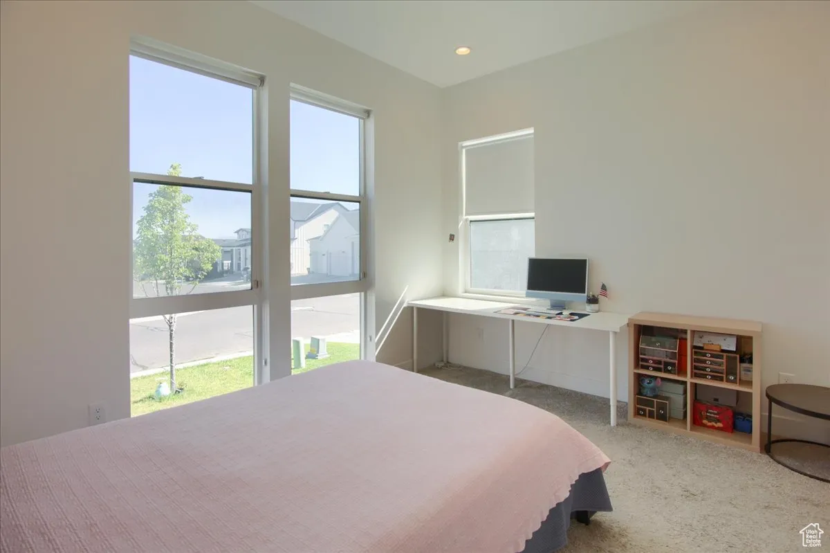 Carpeted bedroom with recessed lighting and a desk