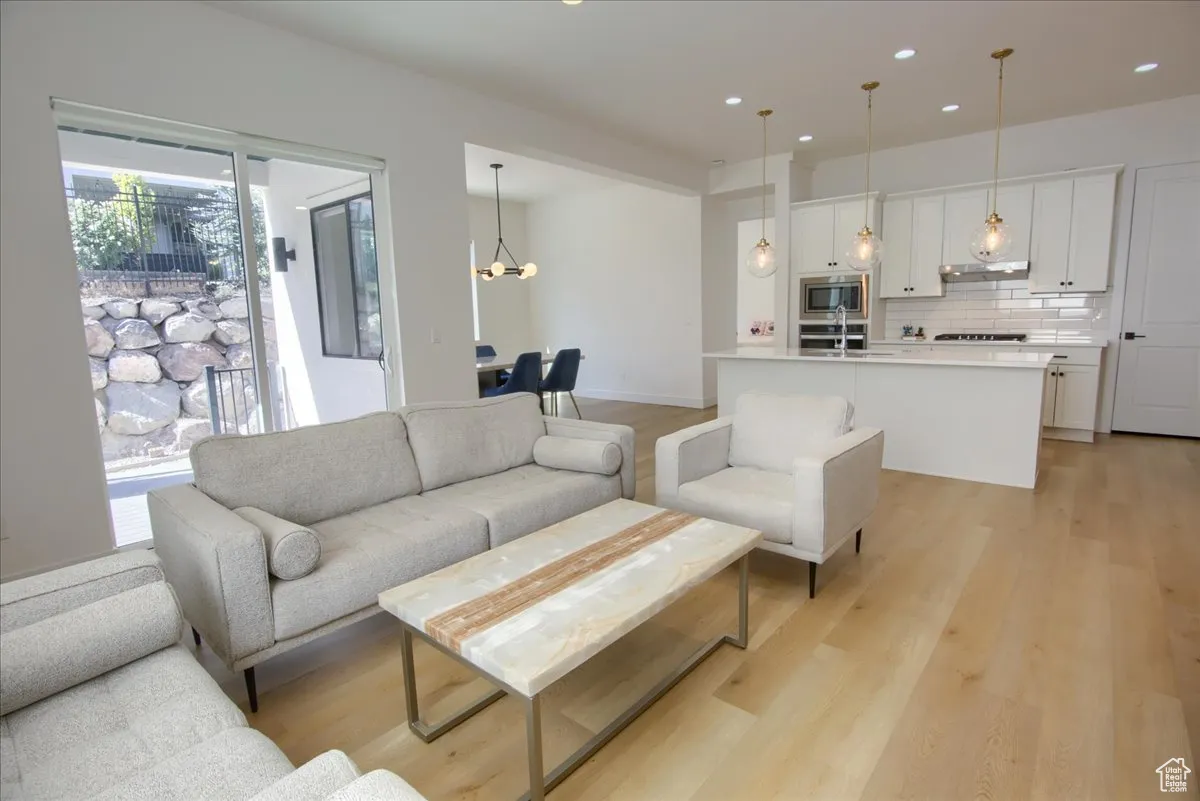 Living room with light wood finished floors, a chandelier, and recessed lighting