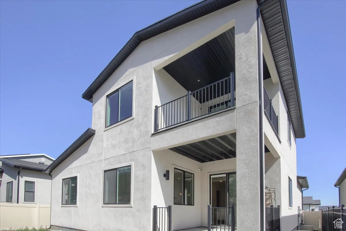 Back of property with a balcony, stucco siding, and a patio