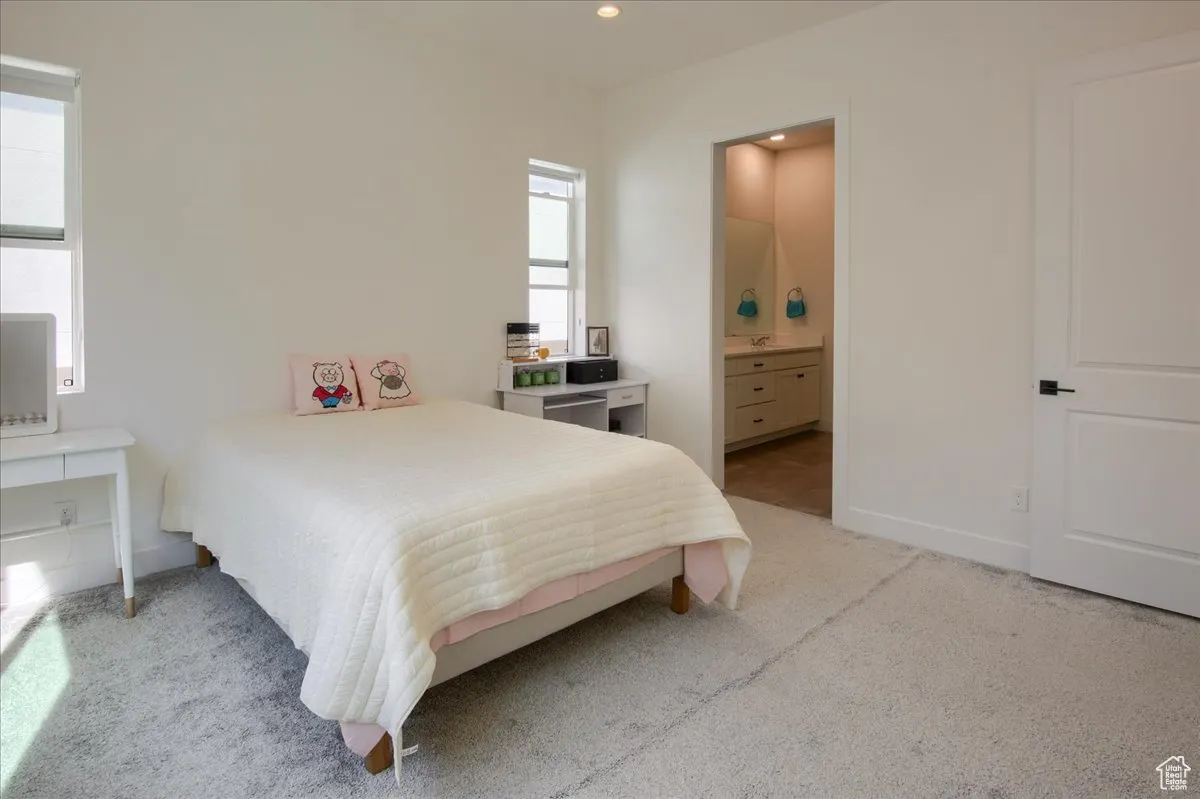 Bedroom featuring light colored carpet, ensuite bathroom, and recessed lighting