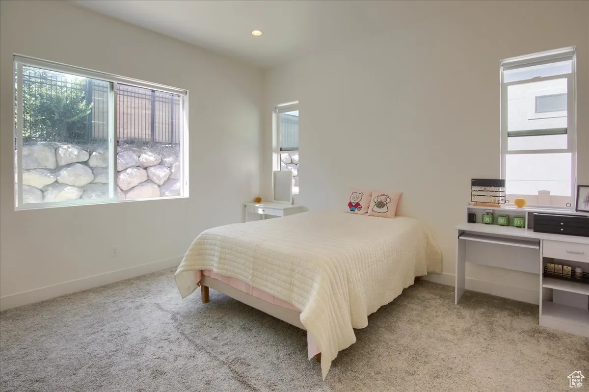 Bedroom featuring light colored carpet, multiple windows, and recessed lighting