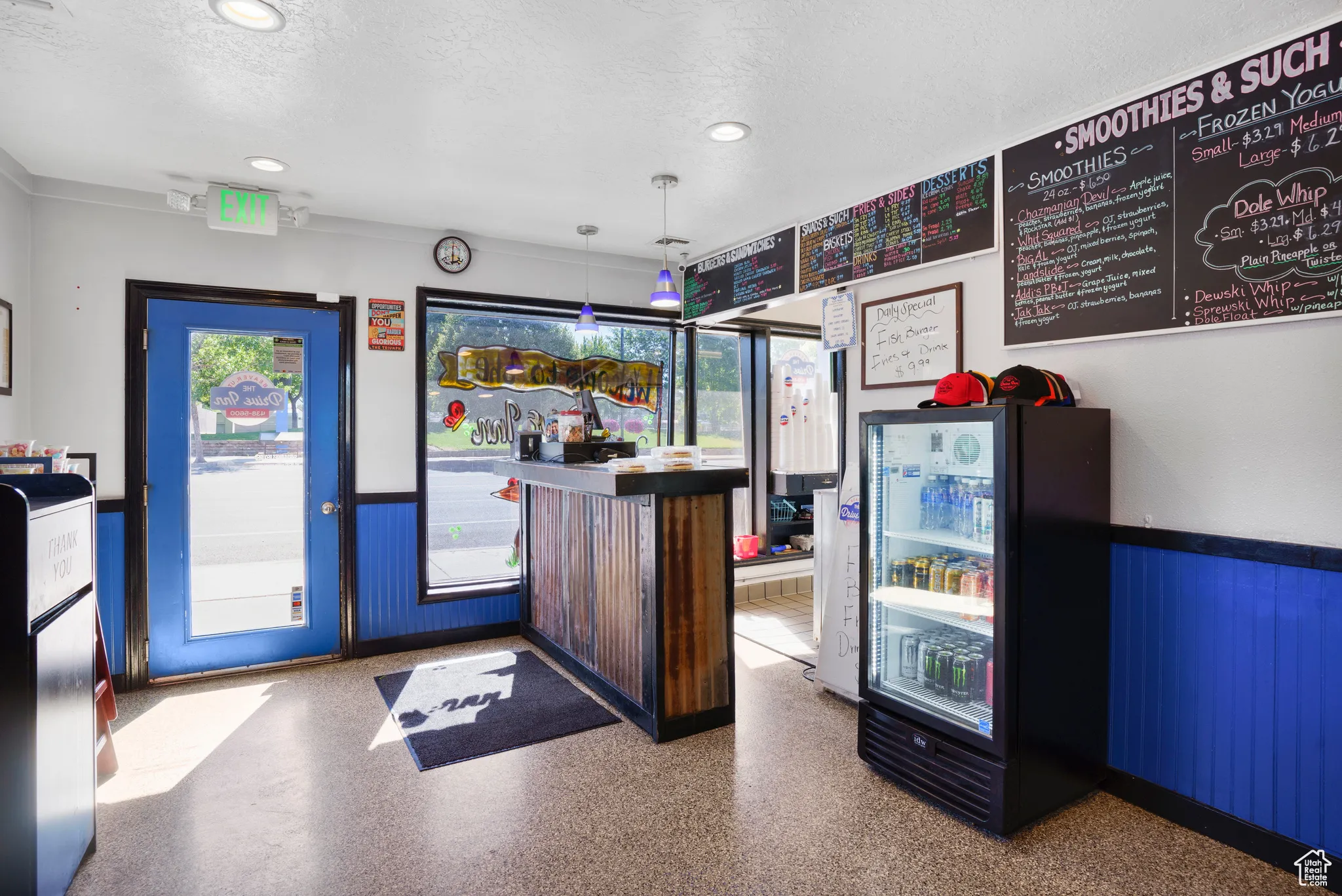 Welcome area with wainscoting, a textured ceiling, wooden walls, recessed lighting, and a bar