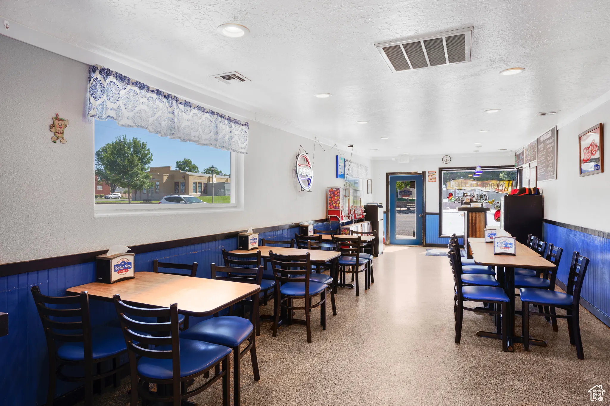 Dining room with a wainscoted wall, a textured ceiling, wooden walls, and recessed lighting