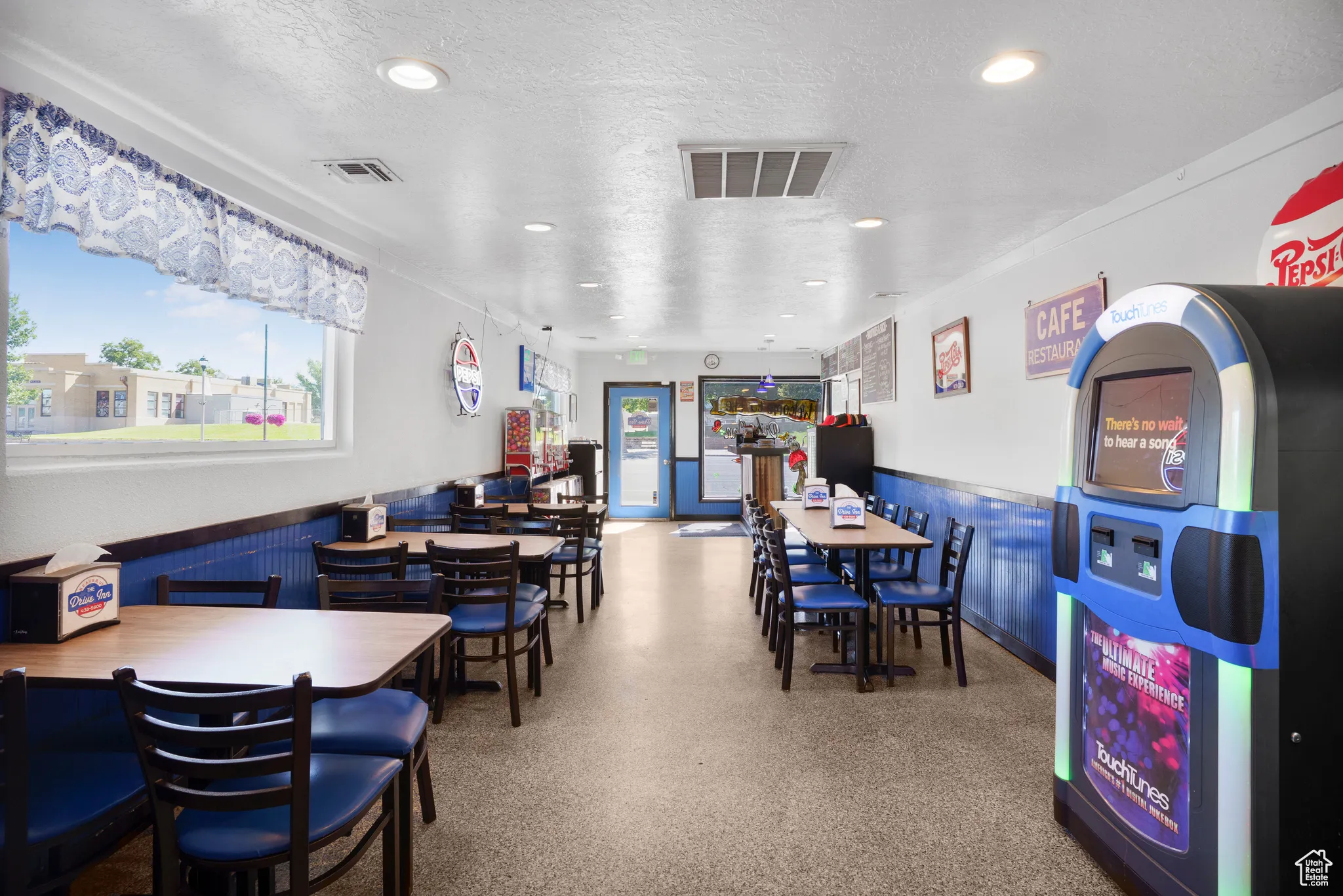 Dining space with a wainscoted wall, a textured ceiling, and recessed lighting