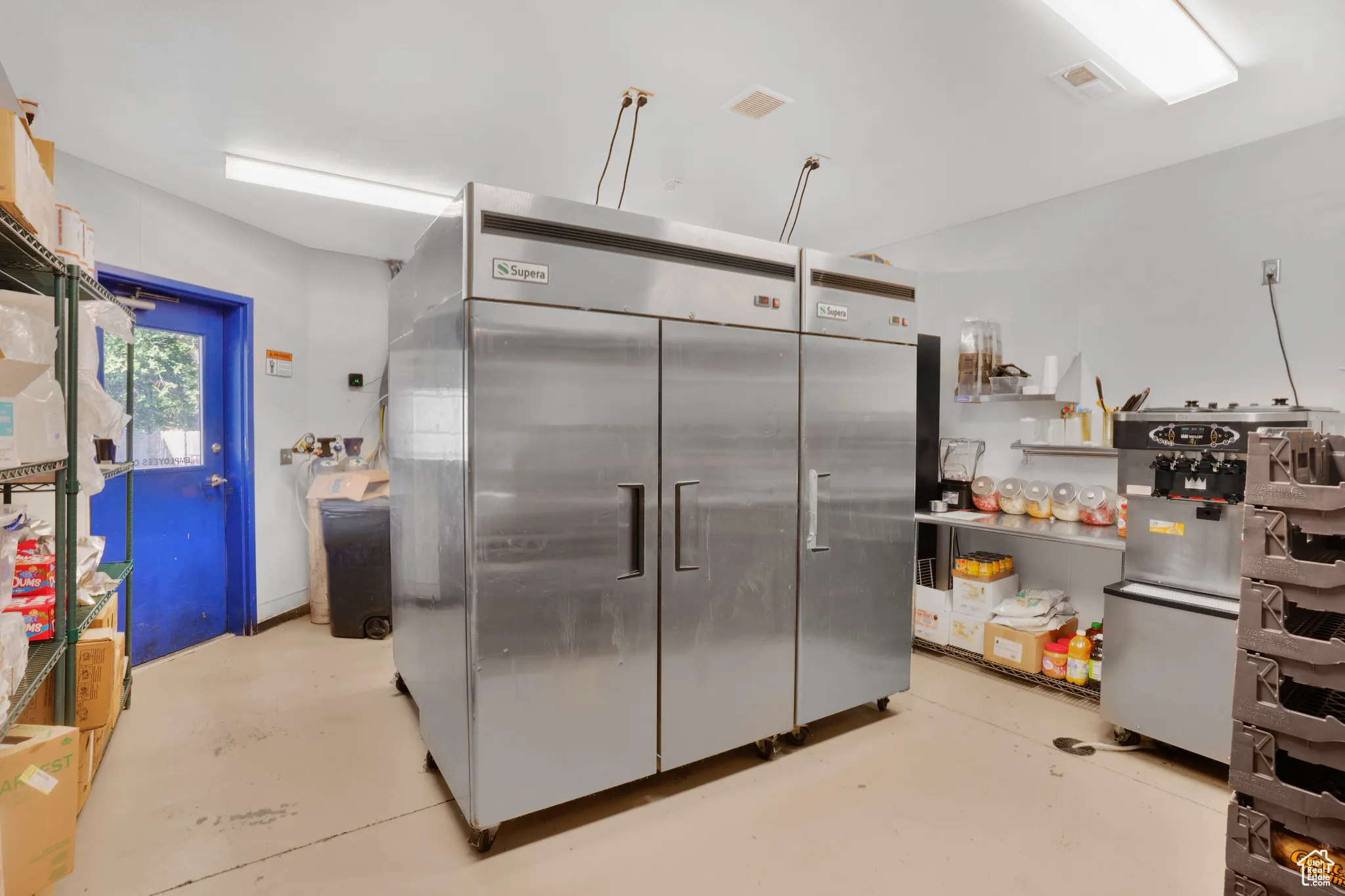 Kitchen with stainless steel fridge, finished concrete flooring, and open shelves