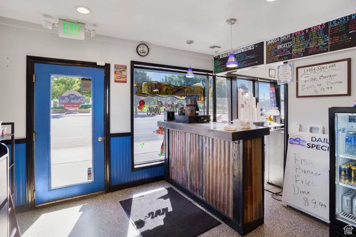 Indoor dry bar featuring a wainscoted wall, hanging light fixtures, recessed lighting, and speckled floor