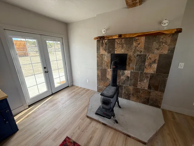 Unfurnished living room with light wood finished floors, french doors, a wood stove, and a textured ceiling