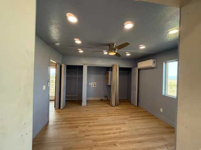 Unfurnished bedroom featuring multiple closets, recessed lighting, a textured ceiling, light wood-style flooring, and a ceiling fan