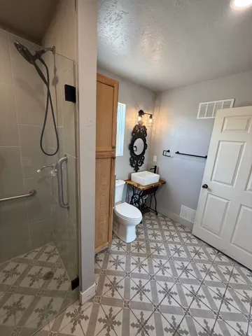 Full bathroom with a shower stall and a textured ceiling