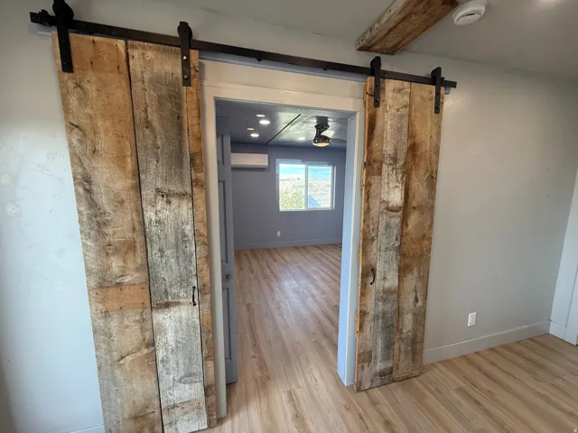 Hall featuring a barn door, light wood-type flooring, and beamed ceiling