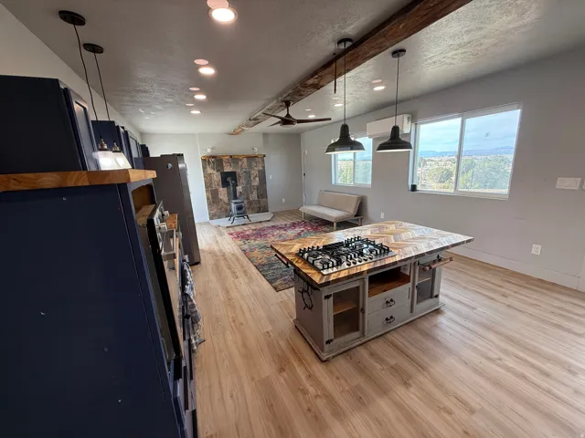 Kitchen with light wood-type flooring, a textured ceiling, a wood stove, freestanding refrigerator, and hanging light fixtures