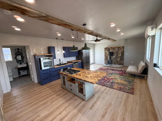 Kitchen with blue cabinets, a wood stove, beamed ceiling, healthy amount of natural light, and light wood-style flooring