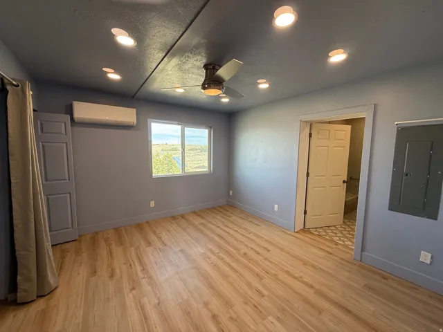 Unfurnished bedroom featuring electric panel, light wood finished floors, recessed lighting, ceiling fan, and a textured ceiling