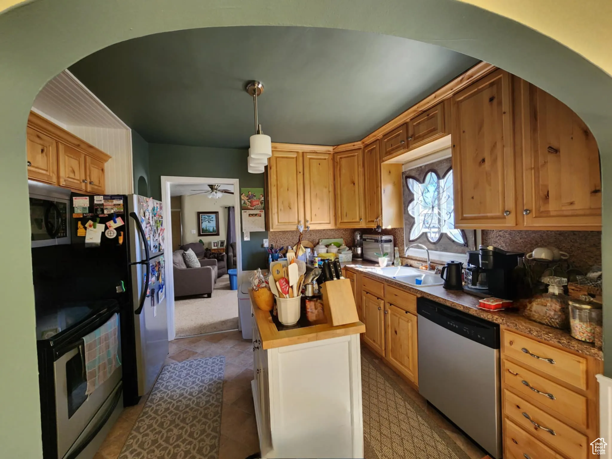 Kitchen featuring appliances with stainless steel finishes, tasteful backsplash, wooden counters, and a ceiling fan