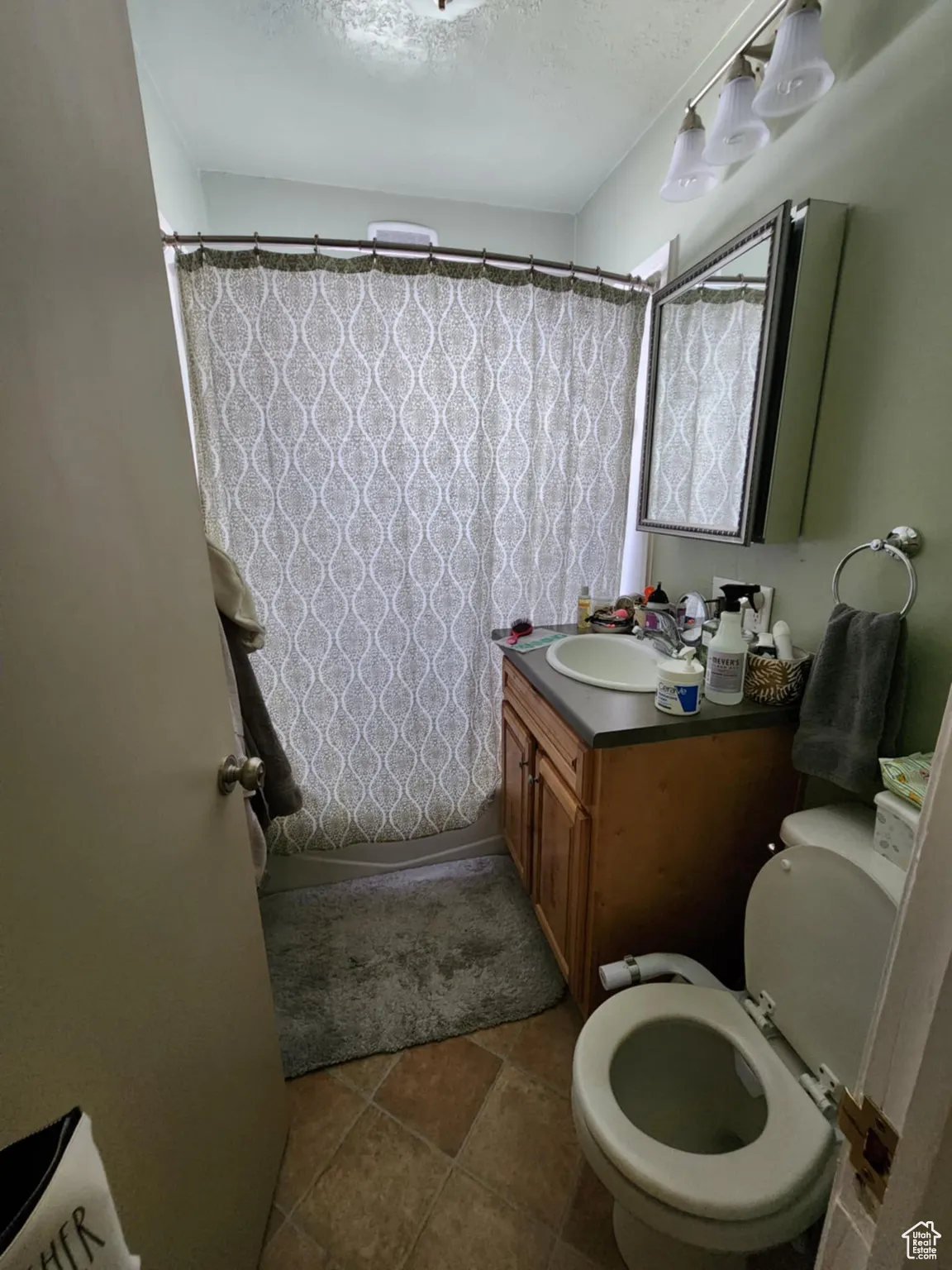 Full bathroom with a textured ceiling, vanity, a shower with shower curtain, and dark tile patterned floors