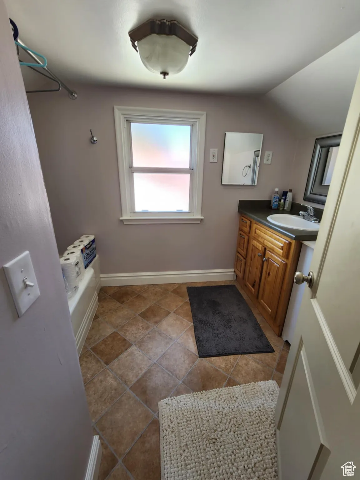 Bathroom featuring vanity, a bath, and lofted ceiling