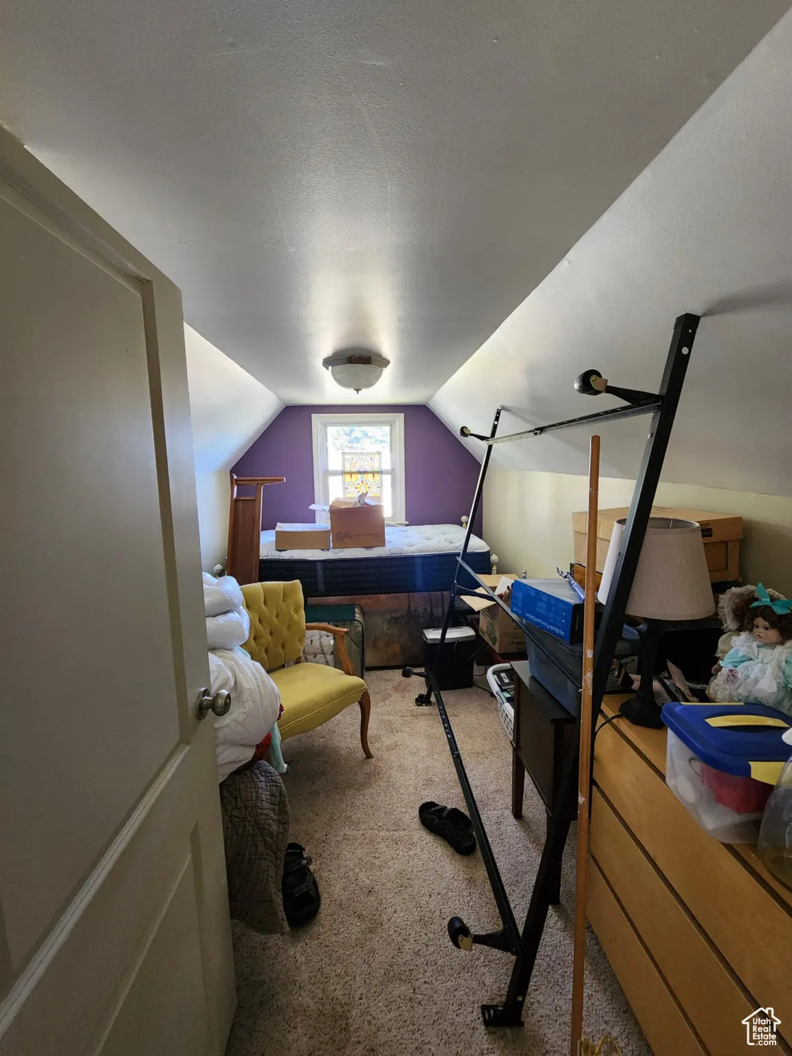 Bedroom featuring vaulted ceiling, light carpet, and a textured ceiling