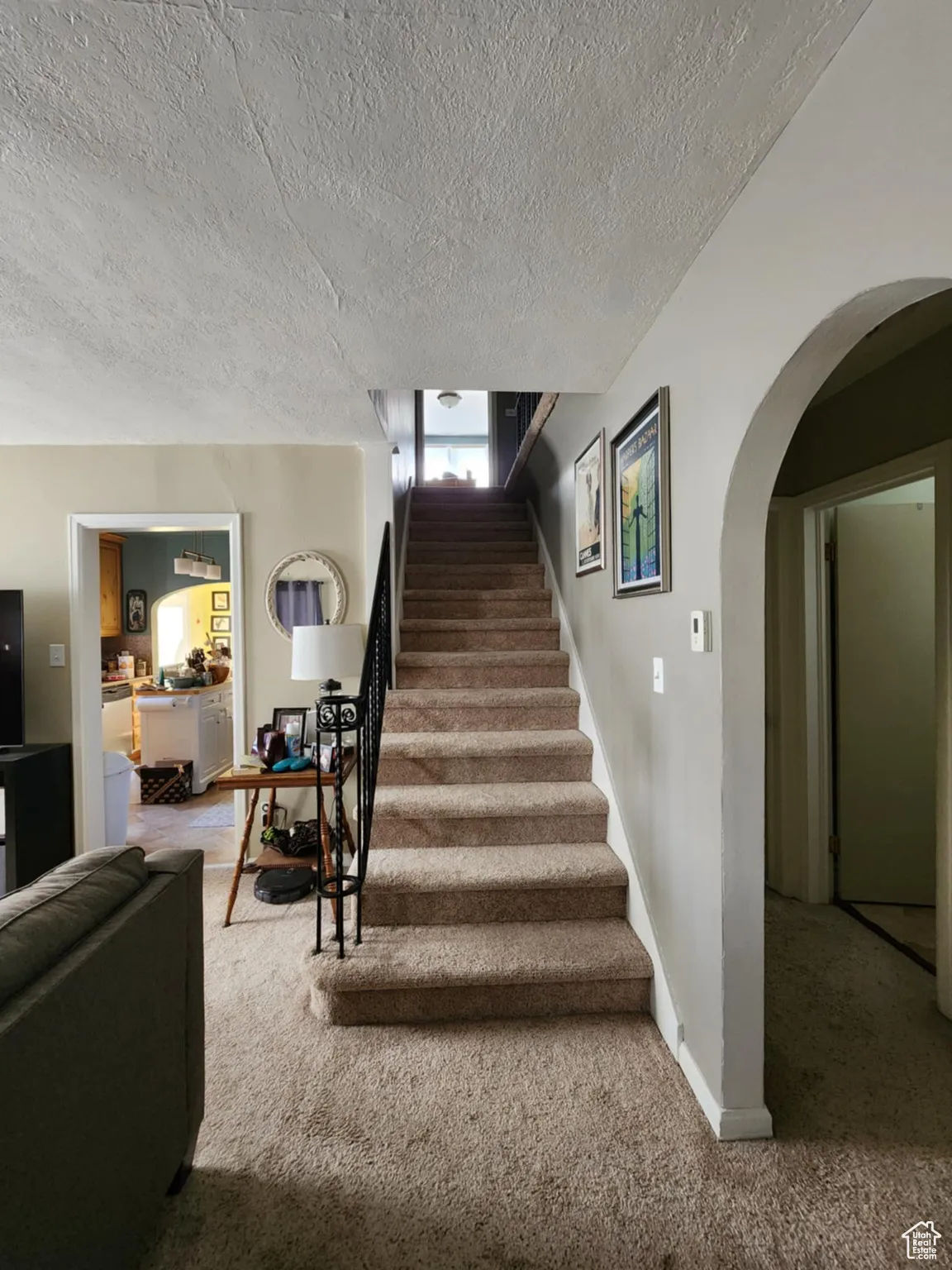 Staircase featuring carpet, arched walkways, and a textured ceiling