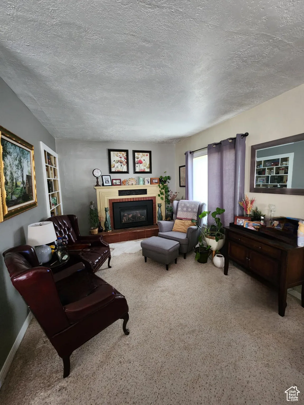 Carpeted living room with a textured ceiling and a glass covered fireplace
