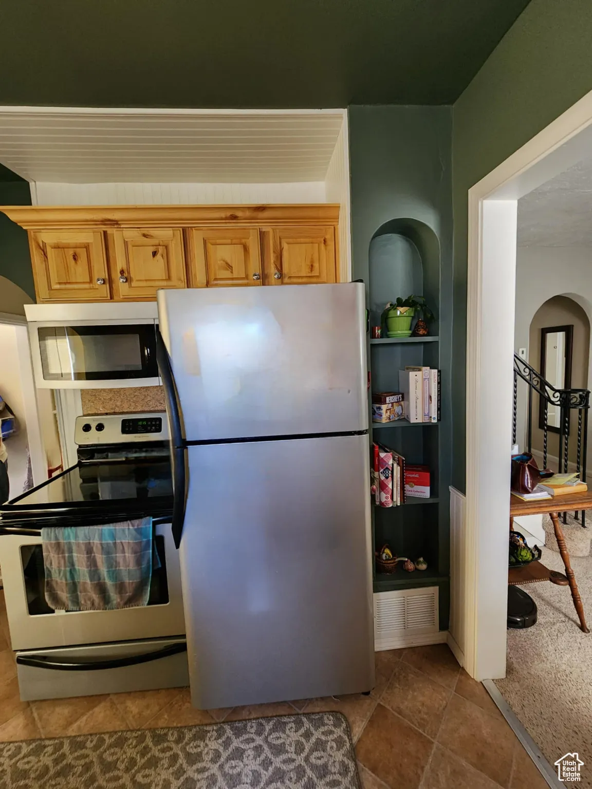 Kitchen with appliances with stainless steel finishes, arched walkways, and light tile patterned flooring