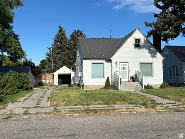 Bungalow-style home with a metal roof, an outdoor structure, concrete driveway, and a garage