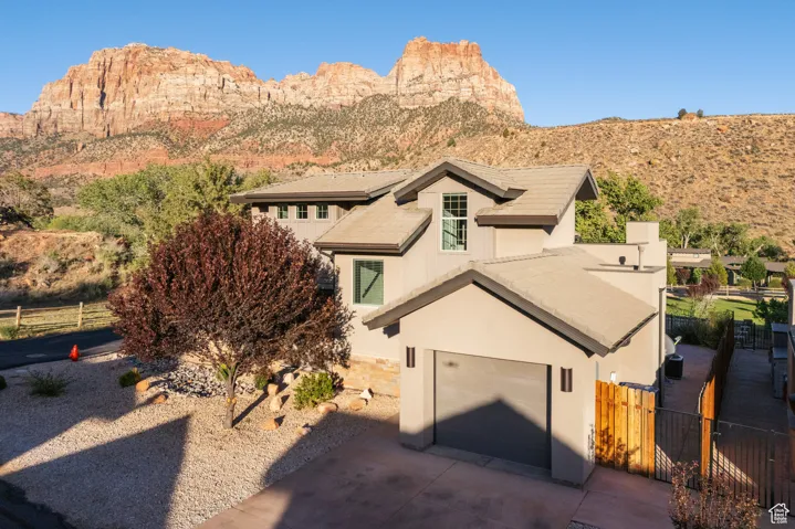 View of front facade featuring a garage, stucco siding, concrete driveway, and a mountain view