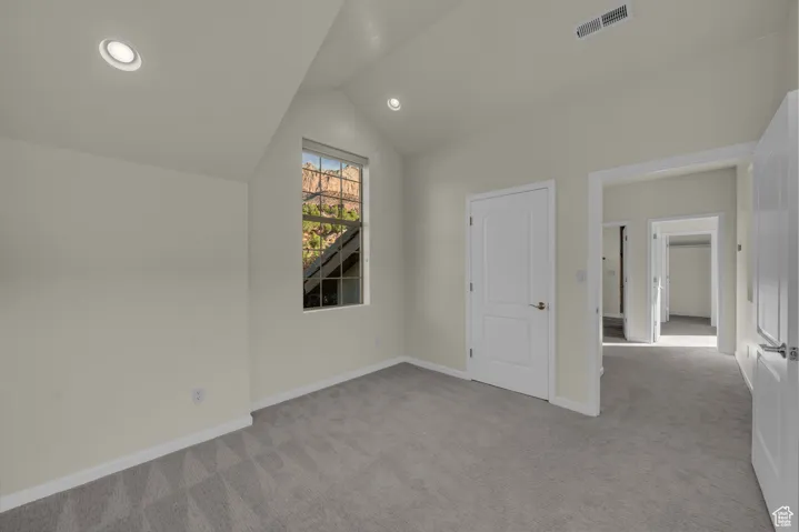 Additional living space with lofted ceiling, light carpet, and recessed lighting
